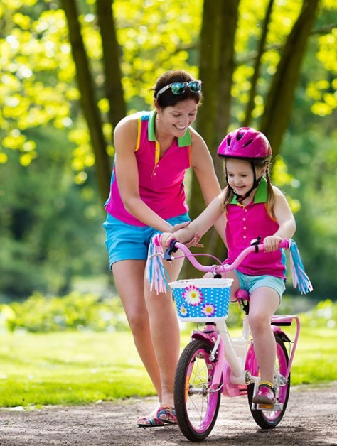 Mom helps child ride a bike
